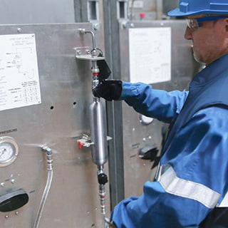 Field engineer inspecting a closed-loop grab sampling system in a chemical plant