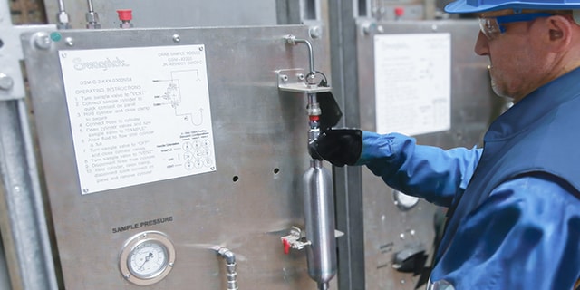 Field engineer inspecting a closed-loop grab sampling system in a chemical plant