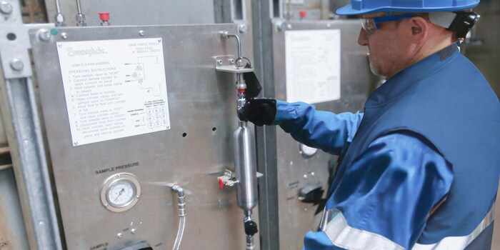 Field engineer inspecting a closed-loop grab sampling system in a chemical plant