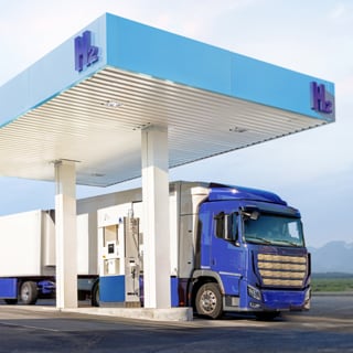 Un camión de gran tonelaje con pila de combustible de hidrógeno repostando en una estación de hidrógeno.