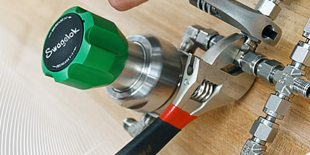 A green Swagelok regulator being installed with a wrench