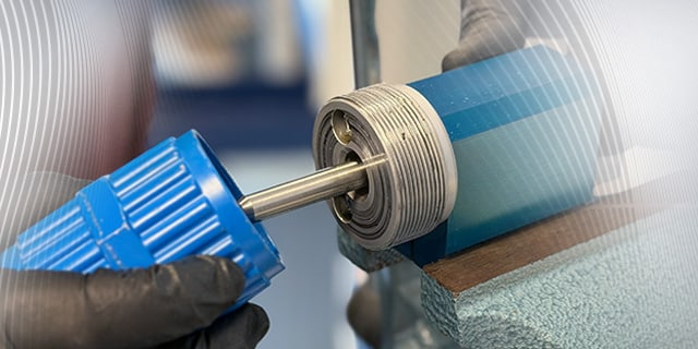 Close‑up of a fluid system fitting being worked on with a precision tool in a workshop environment.