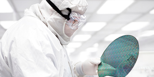 Semiconductor manufacturing technician inspecting a silicon wafer